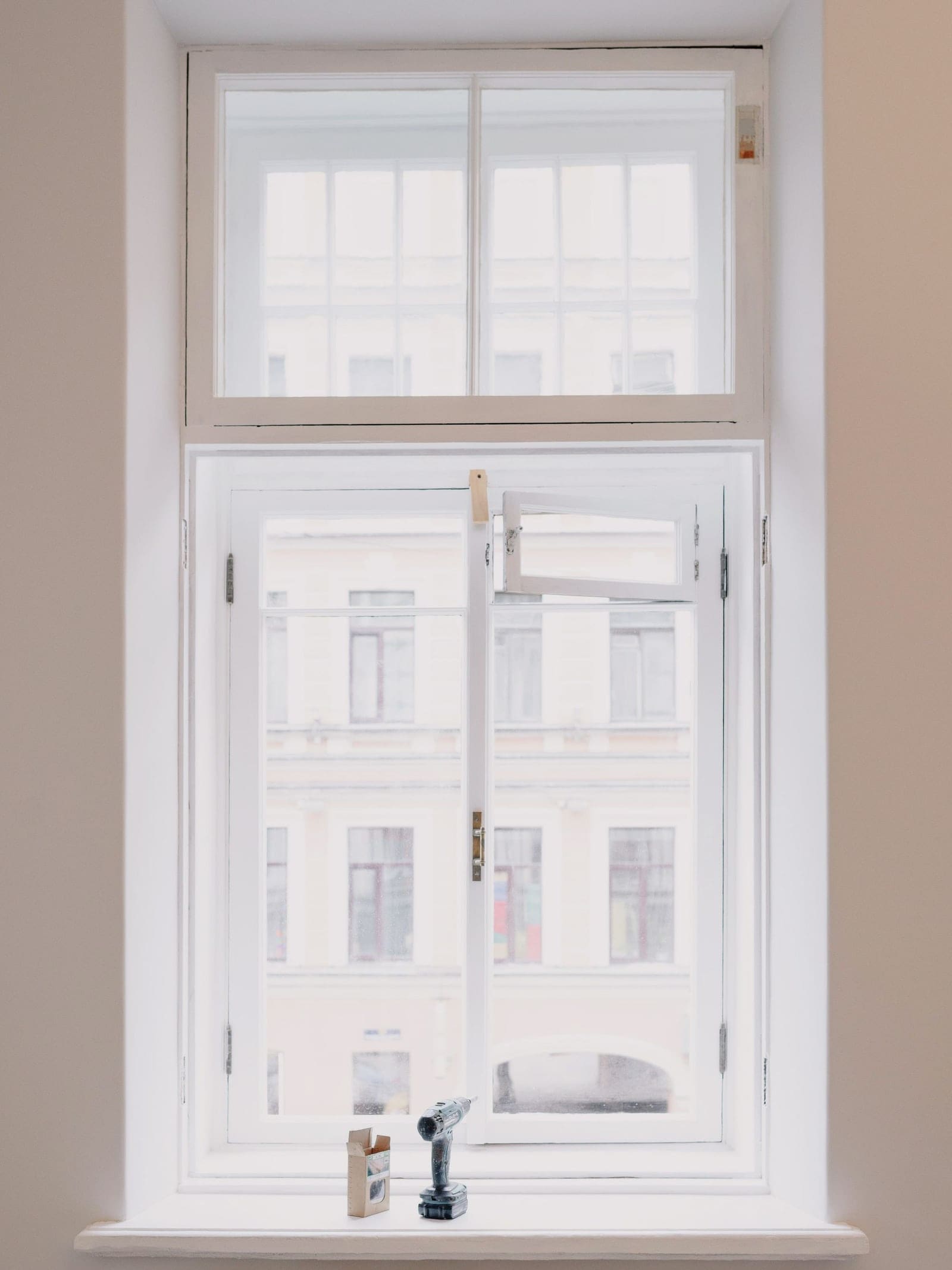 Fenêtre ancienne en bois peinte en blanc, à deux battants et imposte, vue de l’intérieur d’un appartement ancien